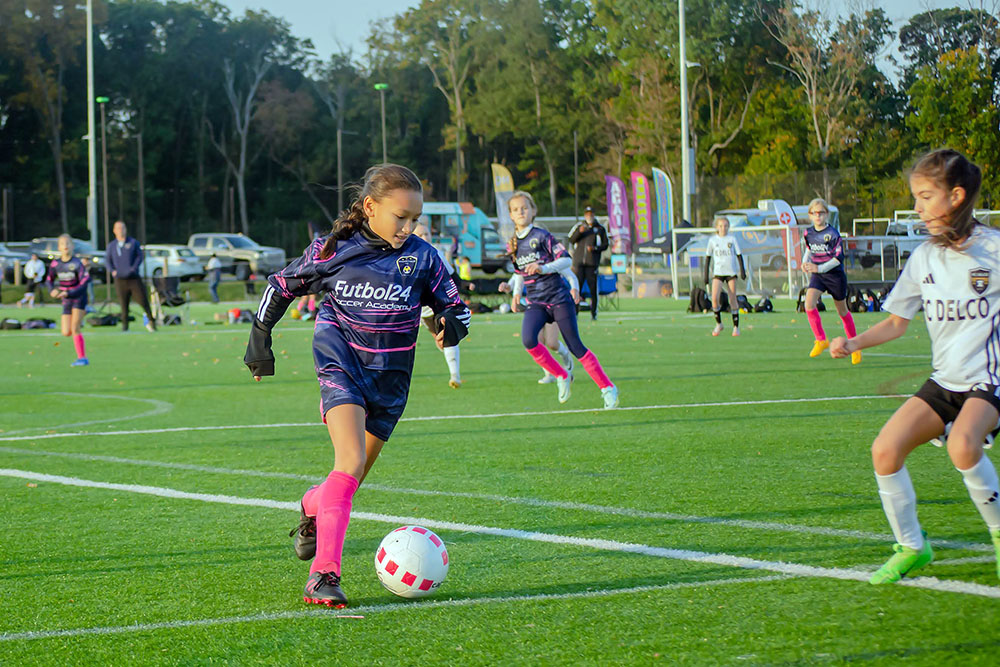 Girl with pink socks dribbles down the field.