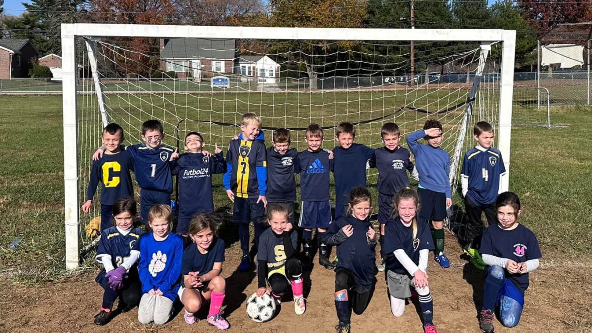 Academy soccer kids in front of a net.