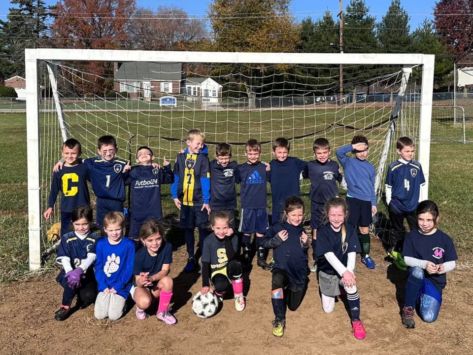 Academy soccer kids in front of a net.