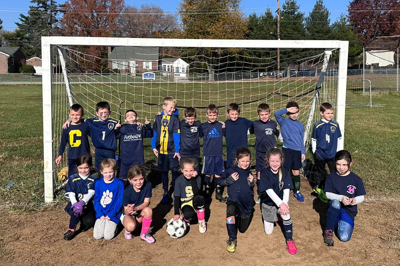 Academy soccer kids in front of a net.