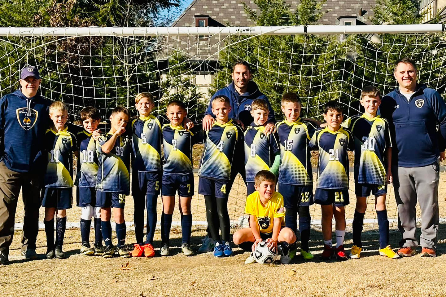 Boys soccer team and coaches in front of a soccer net.